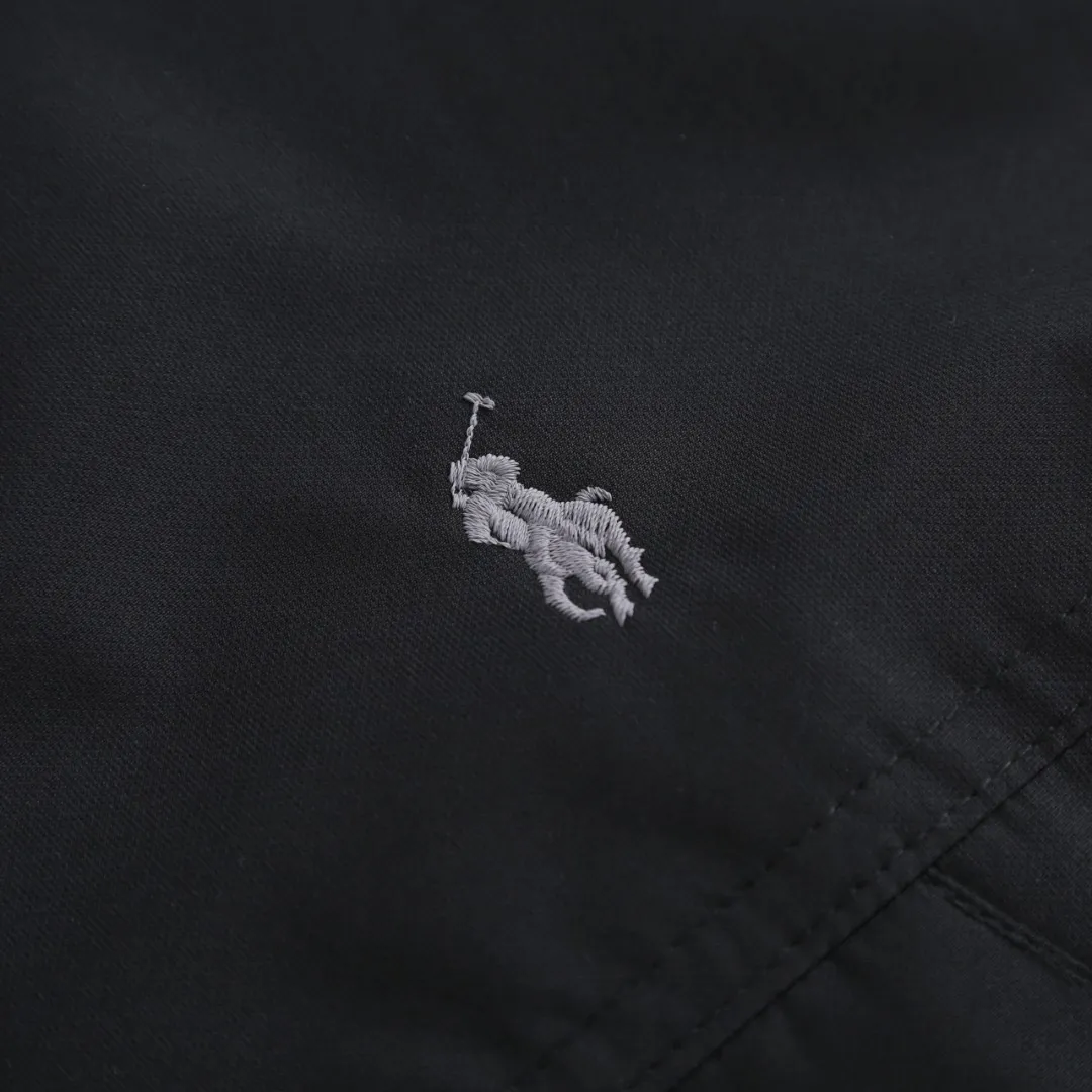 P980 Ralph Lauren Pony Embroidered Hooded Down Jacket (Black) The inner filling is made of high-quality 90 white duck down with a weight of 220g, ensuring excellent thermal insulation performance. After strict screening and processing, the velvet is not easy to get drilled, ensuring durability. The fabric is made of high-density nylon taffeta with a density of about 210T-300T, with a smooth and slightly matte surface, excellent windproof and waterproof properties (with DWR water-repellent treatment), strong wrinkle resistance and easy care, in line with the American casual positioning of "durable and practical". The lining fabric is made of 100% polyamide. The high-density and tight weaving process prevents fine lint from emerging from the gaps in the fabric. The smooth surface improves the putting on and taking off experience, and the excellent wear and tear resistance ensures damage caused by frequent use, while the light and soft texture does not affect the overall weight. The classic jacket has a slightly loose fit, slightly dropped shoulder line (shoulder width is 1-2cm wider than the standard fit), is hip-length, and has slightly tapered straight sleeves, taking into account both freedom of movement and casual style. The adjustable Velcro on the cuffs allows you to freely adjust the tightness according to the thickness of your wrist and personal preferences, effectively preventing cold wind from intruding, and improving the warmth performance. In terms of storage, the two front zipper pockets are convenient for you to place frequently used items, and the zipper design ensures that items are not easily lost. A built-in pocket on the left side of the chest provides a safe storage space for some small private items. The drawstring design at the hem allows you to adjust the shape of the jacket according to your body shape and dressing needs. Whether it is loose and casual or slim and neat, you can easily control it. Polo horse logo on the left chest: flat satin stitch embroidery (satin embroidery), the embroidery thread is 100% polyester high color fastness embroidery thread (the color number is consistent with the brand's standard red color card), the stitch density is 12-15 stitches/cm, the outline of the horse logo is clear, and the details of the rider and horse are burr-free. Size:S-M-L-XL